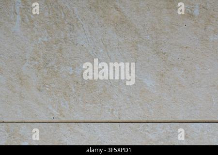 Light beige tile with natural uneven texture, diagonal pattern lines and a clearly visible horizontal tile joint Stock Photo