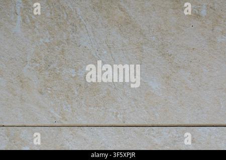 Light beige tile with natural uneven texture, diagonal pattern lines and a clearly visible horizontal tile joint Stock Photo