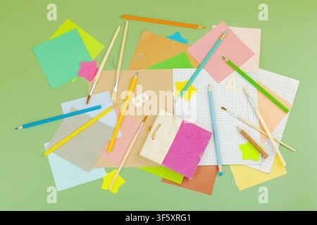 Eco-friendly school supplies on green background. Unbleached paper, wooden pencils, brushes, notebooks for sustainable plastic free back to school con Stock Photo