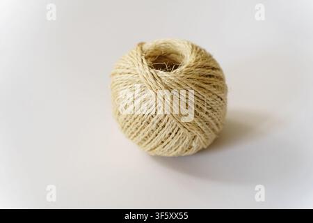 Closeup of a ball of natural jute twine on a neutral surface, perfect for rustic packaging, crafting projects, or gardening tasks Stock Photo