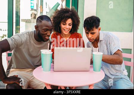 Friends bond through digital experiences, exploring content together on a laptop enjoying technology Stock Photo