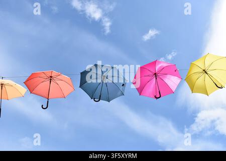 Colorful hanging umbrellas against a bright blue sky Stock Photo