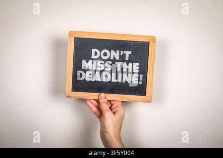 DONT MISS THE DEADLINE! warning concept displayed on handheld blackboard with copy space Stock Photo