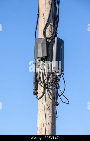 Communication Network Devices Installed on Utility Pole Against Clear Blue Sky Background Stock Photo