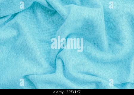 Crumpled light blue knitted cotton fabric texture with soft delicate drapery folds and ribbed weave structure for pastel sewing and casual apparel bac Stock Photo