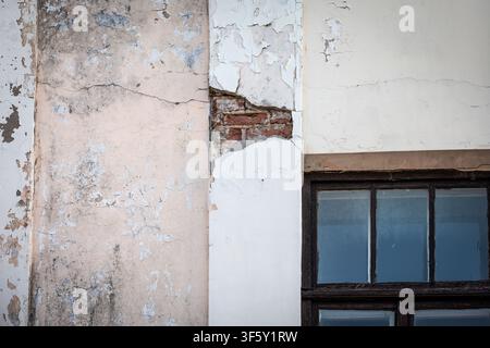 Old Wall Surface With Peeling Paint Cracks and Visible Brick Under Plaster Stock Photo