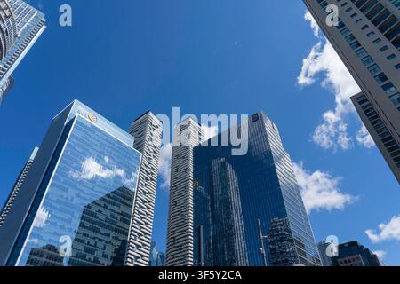 Low angle view of modern high-rise commercial and residential towers against a bright blue sky with white clouds in Toronto Stock Photo