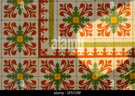 Close-up of vintage encaustic floor tiles illuminated by natural sunlight and tree shadows. Stock Photo