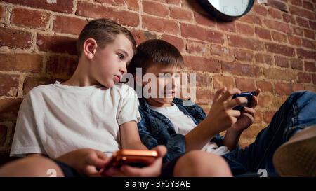Two focused boys using smartphones together during leisure time at home Stock Photo