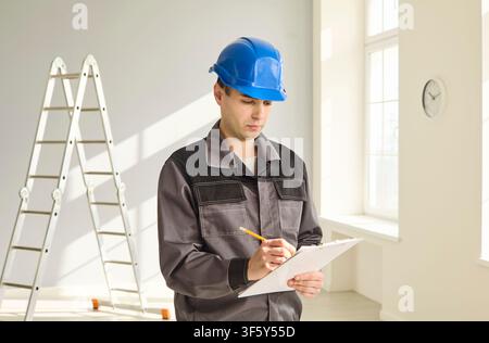 Construction worker in helmet with clipboard inspecting renovation site indoors Stock Photo
