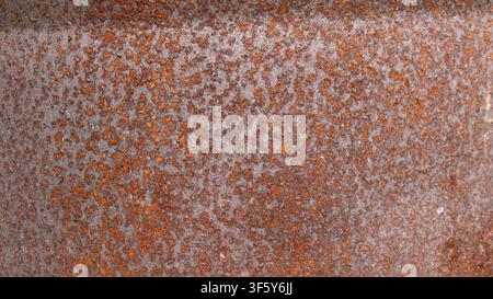 heavily rusted sheet of metal. The surface is covered in a dense layer of red and brown corrosion with a rough texture. The old gray base of the iron Stock Photo