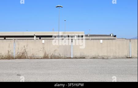 Concrete boundary wall with an industrial area and sky on behind. Street in front. Background for copy space. Stock Photo