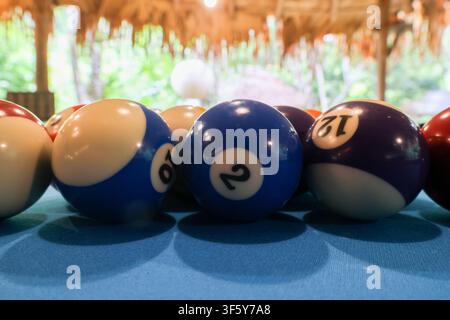 A blue and purple numbered billiard balls lined on teal pool table cloth in relaxed indoor game setting with soft natural light and tropical backgroun Stock Photo