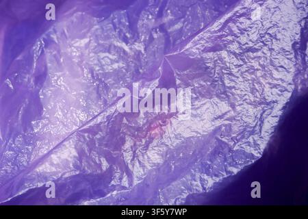 A crinkled purple plastic texture glossy surface with light reflections and creases, abstract close up evoking fragile material and subtle sheen Stock Photo