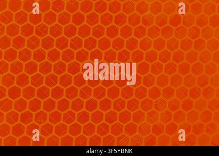 An orange honeycomb textured pattern with diagonal scratches creating dynamic abstract background, bright geometric surface evokes energy and modern d Stock Photo