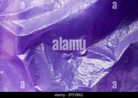 A purple crumpled plastic texture with glossy wrinkles and light reflections, abstract background conveying tactile sheen and subtle depth Stock Photo