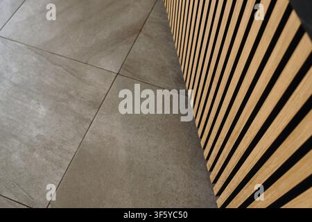 Minimalist interior detail featuring wooden slat wall panels and gray tile flooring. Contemporary architectural background with clean geometric lines. Stock Photo