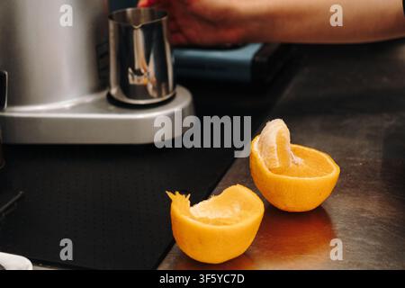 Barista prepares fresh juice behind the counter using professional equipment. Natural ingredients and beverage preparation in a modern cafe kitchen. Stock Photo