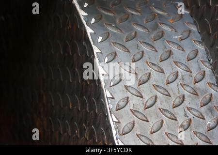 A worn metal diamond plate stair tread with rust spots and textured raised pattern conveying industrial grit and tactile detail Stock Photo