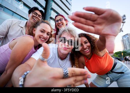 Group of happy young friends taking a selfie, gesturing at the camera. Stock Photo