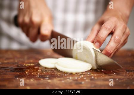 Chef slicing onion on wooden cutting board Stock Photo