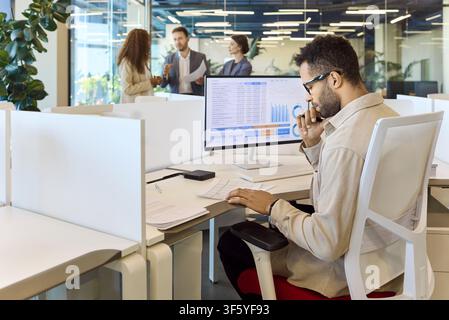 Business manager analyzing spreadsheet data at desktop monitor in bright office Stock Photo