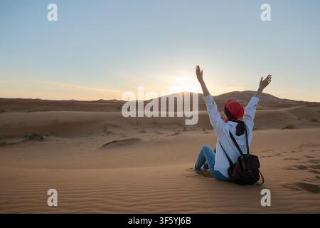 Lonely woman sitting on the sand in the vast desert , contemplating solitude and nature Stock Photo