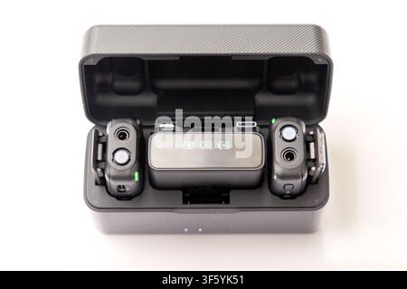 An open black charging case containing two wireless microphone transmitters and a central receiver unit against a white background Stock Photo