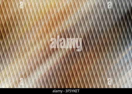 A textured surface with a diagonal ribbed pattern, displaying a mix of rustic stone, brown, and metallic grey tones with soft lighting. Stock Photo