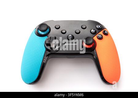 A modern black video game controller with blue and orange textured grips is shown isolated on a white background Stock Photo