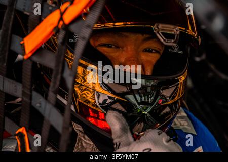 Extreme close-up portrait of a professional race car driver inside the cockpit wearing a custom gold and black helmet with visor open, looking through Stock Photo