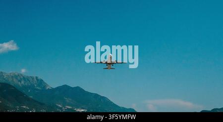 Tivat, Montenegro - June 25, 2026. Passenger aircraft descends toward the runway at Tivat Airport against a clear blue sky and mountain landscape. Stock Photo