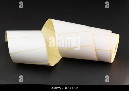 Rolls of blank white adhesive labels isolated on white for direct thermal and thermal transfer printing, packaging, pricing and retail use. Stock Photo