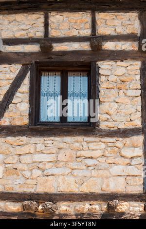 Whispering timber lines framing a lace‑veiled window in rustic stonework (Calatañazor, Spain: 18-jul-2026) Stock Photo