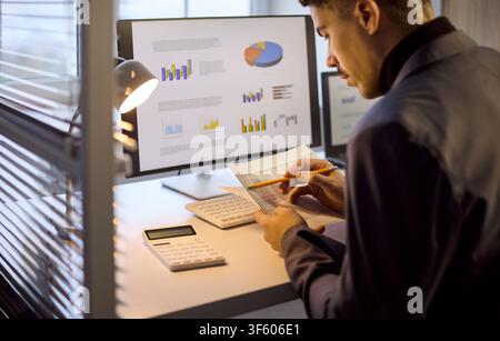 Businessman manager analyzing charts on laptop at office desk, finance data review Stock Photo