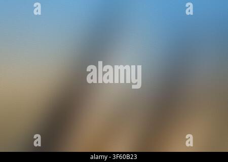 An abstract background image showing a frosted glass surface with a blend of soft blue and warm brown light gradients, creating a moody atmosphere. Stock Photo