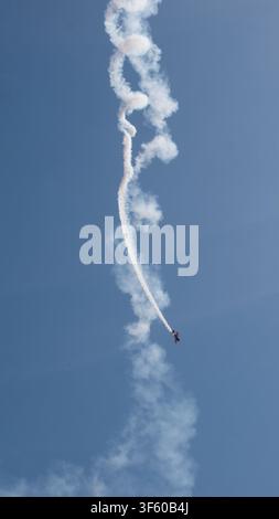 Aerobatic Biplane Trailing a White Smoke Spiral Against a Clear Blue Sky at an Air Show — Precision Flying, Freedom and Adventure Concept Stock Photo