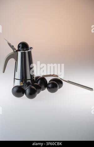 Vertical studio still life of multiple black painted eggs grouped abundantly with a stainless steel moka pot and spoon on a warm peach gradient backgr Stock Photo