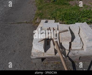 Weathered pickaxe resting on stacked granite blocks  Stock Photo