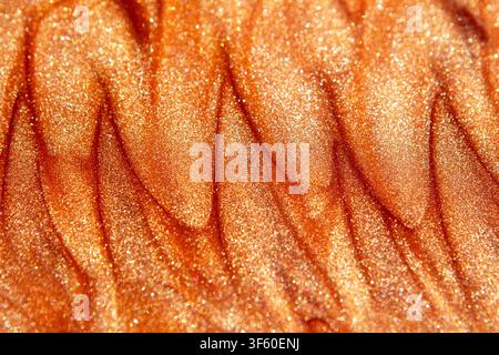 Macro orange glitter texture with shimmering metallic waves and abstract sparkle background Stock Photo