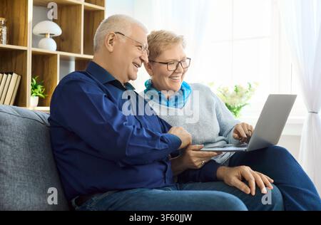 Smiling senior couple using laptop at home for online learning and connection Stock Photo