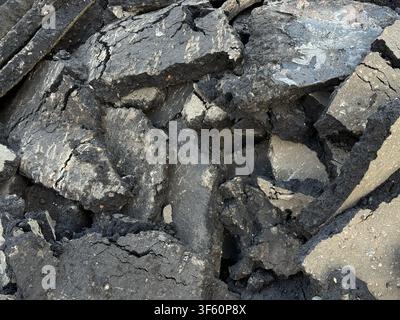Cracked asphalt pieces creating textured urban background with rugged surface details. Mobile photo Stock Photo