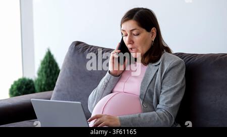 Pregnant woman working from home using laptop and phone Stock Photo