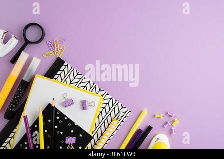 Flat lay composition featuring stationery items like notebooks, pencils, markers, and paper clips arranged on a vibrant purple surface. Ideal for educ Stock Photo