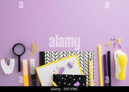 Collection of stationery items including notebooks, pens, paper clips, stapler, magnifying glass, and push pins arranged on a purple background. Ideal Stock Photo