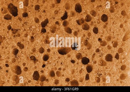 Macro, closeup of orange foam sponge texture with porous, spongy and bubbly surface pattern suitable for abstract background design. Foamed polyuretha Stock Photo