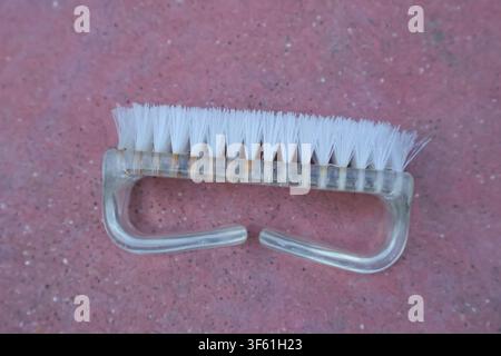 Small white cleaning brush with plastic handle on pink background. Stock Photo
