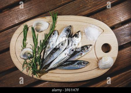 Fresh Horse Mackerel on Wooden Board with Rosemary Stock Photo