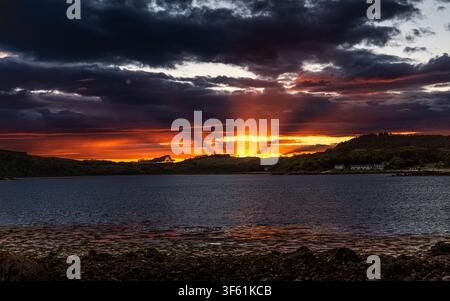 Dramatic sunset behind Rockcliffe village and Grennan Hill viewed across Rough Firth from beach at Portobeagle in Dumfries & Galloway, Scotland, UK Stock Photo