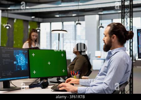 Programmer in office using AI automation scripts on green screen computer to reduce repetitive coding tasks. IT expert using artificial intelligence technology on chroma key PC Stock Photo